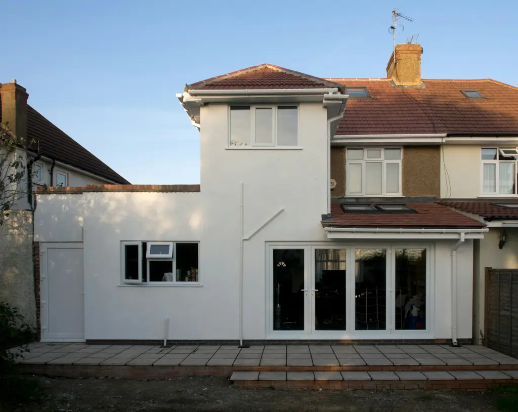 Rendered two-storey rear extension with white bi-fold doors on a semi-detached house in West London